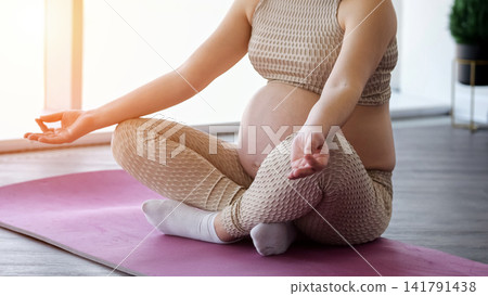 Pregnant woman practicing yoga and meditation for wellness Pregnant woman practicing yoga and meditation for wellness 141791438