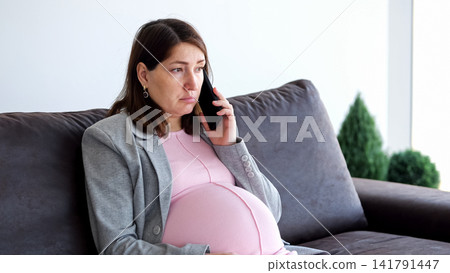 Pregnant woman having emotional phone call while sitting Pregnant woman having emotional phone call while sitting 141791447