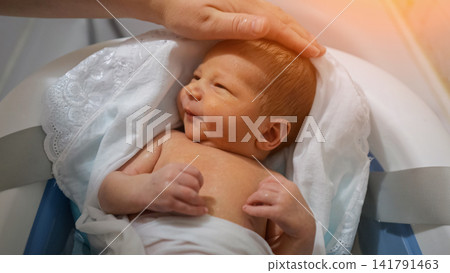 Parent gently washing baby's head in a bath Parent gently washing baby's head in a bath 141791463