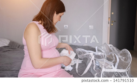 Pregnant woman packing hospital bag, preparing for baby delivery Pregnant woman packing hospital bag, preparing for baby delivery 141791510