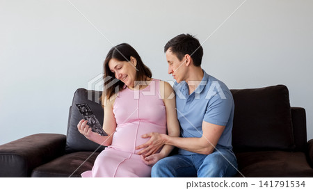 Pregnant happily viewing ultrasound scan at home 141791534