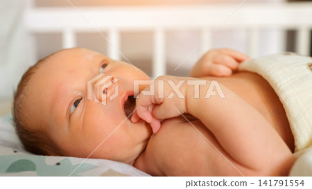 Newborn baby awake laying in crib early morning light Newborn baby awake laying in crib early morning light 141791554