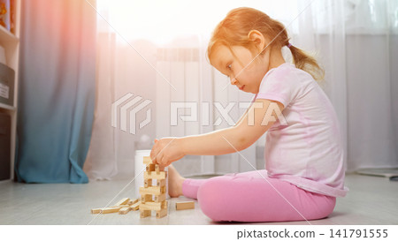 Little girl playing with wooden blocks building tower Little girl playing with wooden blocks building tower 141791555