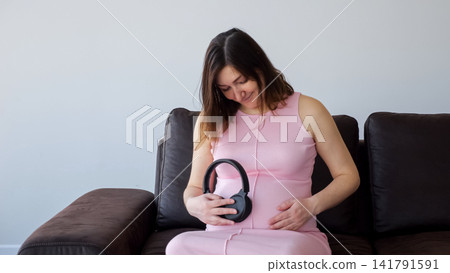 Pregnant woman playing music to developing baby Pregnant woman playing music to developing baby 141791591