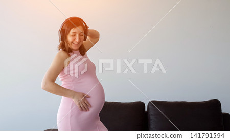 Pregnant woman enjoying music and dancing with headphones Pregnant woman enjoying music and dancing with headphones 141791594
