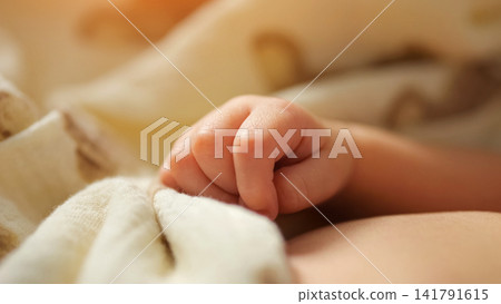 Baby hand softly clutching fabric while peacefully sleeping Baby hand softly clutching fabric while peacefully sleeping 141791615