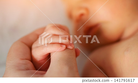 Newborn baby holding parent's finger in loving gesture Newborn baby holding parent's finger in loving gesture 141791617