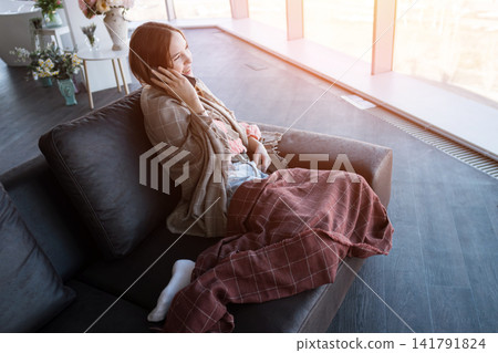 Woman relaxing on couch talking on mobile phone Woman relaxing on couch talking on mobile phone 141791824