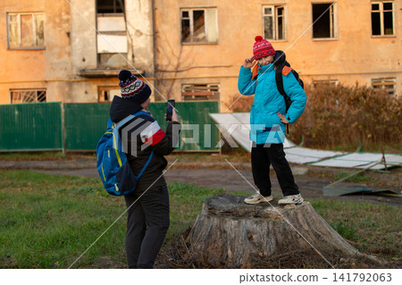 Children wearing winter clothing taking a photo outside an abandoned building Children wearing winter clothing taking a photo outside an abandoned building 141792063