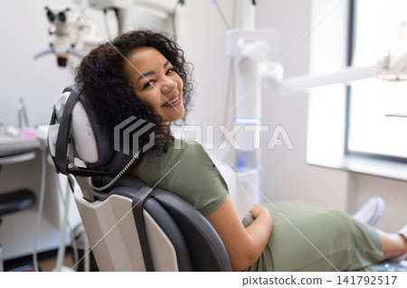 Relaxed black female patient smiling in a dental chair before examination Relaxed black female patient smiling in a dental chair before examination 141792517