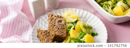 A plate holds boiled potatoes, turkey meat pie, broccoli, and green peas. This breakfast is healthy and gluten free, perfect for a good start to the day, banner A plate holds boiled potatoes, turkey meat pie, broccoli, and green peas. This breakfast is healthy and gluten free, perfect for a good start to the day, banner 141792756