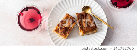 Delicious gluten free pear pie sits on a plate next to a berry drink. A bowl of pie is in the background. The scene is set for breakfast or lunch, banner 141792760