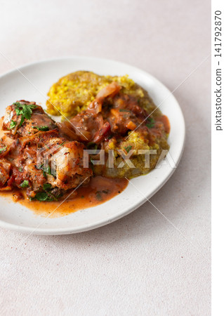 Servings of porridge mix with amaranth, millet, and quinoa sit next to baked white hake covered in tomato sauce. This meal is healthy and gluten-free Servings of porridge mix with amaranth, millet, and quinoa sit next to baked white hake covered in tomato sauce. This meal is healthy and gluten-free 141792870
