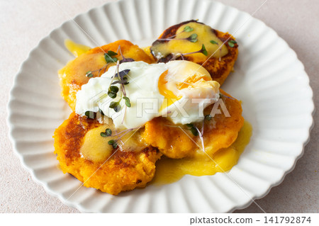 Millet pancakes are served on a plate with hollandaise sauce and a poached egg. This meal is ideal for anyone looking for a healthy breakfast or lunch option Millet pancakes are served on a plate with hollandaise sauce and a poached egg. This meal is ideal for anyone looking for a healthy breakfast or lunch option 141792874