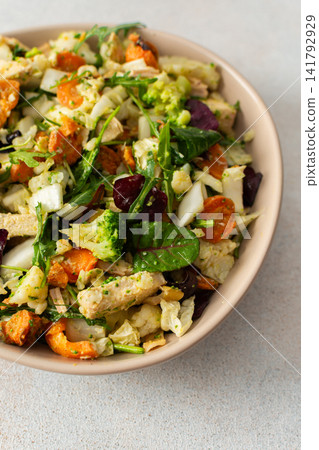 Baked chicken breast is mixed with chopped carrots, broccoli, cauliflower, and fresh herbs in a bowl. This dish is ideal for a nutritious breakfast or lunch meal Baked chicken breast is mixed with chopped carrots, broccoli, cauliflower, and fresh herbs in a bowl. This dish is ideal for a nutritious breakfast or lunch meal 141792929
