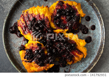 Millet pancakes are arranged on a plate and topped with currant sauce. The scene displays a simple breakfast setting at home in the morning Millet pancakes are arranged on a plate and topped with currant sauce. The scene displays a simple breakfast setting at home in the morning 141792931