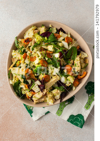 Baked chicken breast is mixed with chopped carrots, broccoli, cauliflower, and fresh herbs in a bowl. This dish is ideal for a nutritious breakfast or lunch meal Baked chicken breast is mixed with chopped carrots, broccoli, cauliflower, and fresh herbs in a bowl. This dish is ideal for a nutritious breakfast or lunch meal 141792979