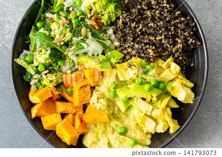 A bowl filled with quinoa, roasted pumpkin, hummus, and a salad of fresh avocado is ready to eat. This meal is gluten free and offers a healthy start to the day A bowl filled with quinoa, roasted pumpkin, hummus, and a salad of fresh avocado is ready to eat. This meal is gluten free and offers a healthy start to the day 141793073