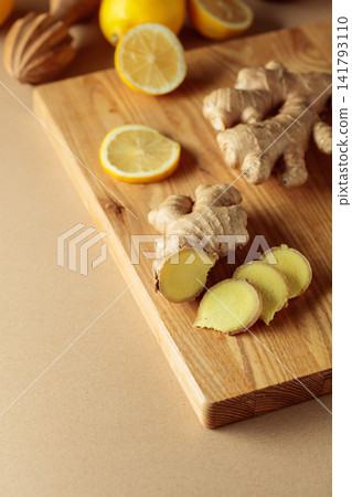 Ginger roots and fresh lemons on a cutting board. Ginger roots and fresh lemons on a cutting board. 141793110