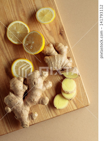 Ginger roots and fresh lemons on a cutting board. Ginger roots and fresh lemons on a cutting board. 141793112