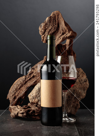 Red wine with old snag and a piece of granite rock on a black background. Red wine with old snag and a piece of granite rock on a black background. 141793298