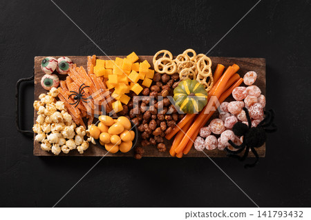 Halloween party snack platter with candy and popcorn on black background Halloween party snack platter with candy and popcorn on black background 141793432