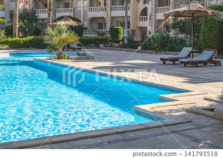 Luxury tropical resort swimming pool and garden landscaping. Modern architecture with tropical palms Luxury tropical resort swimming pool and garden landscaping. Modern architecture with tropical palms 141793518