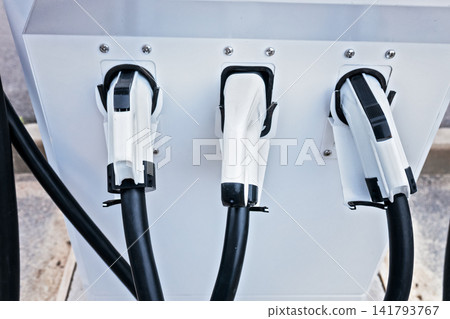 Three electric vehicle charging connectors plugged into public EV station close up Three electric vehicle charging connectors plugged into public EV station close up 141793767