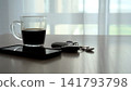 A Tranquil Morning Scene Featuring a Cup of Coffee, Smartphone, and Car Keys Set Against a Soft, Sunlit Background. 141793798