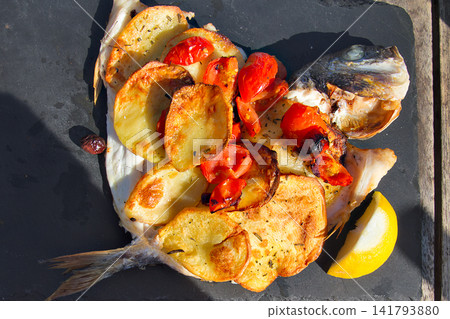 Baked whole dorada fish with roasted potatoes and cherry tomatoes Baked whole dorada fish with roasted potatoes and cherry tomatoes 141793880