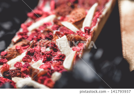 Melted white artisan chocolate bar with freeze dried raspberries and nutty inclusions Melted white artisan chocolate bar with freeze dried raspberries and nutty inclusions 141793937