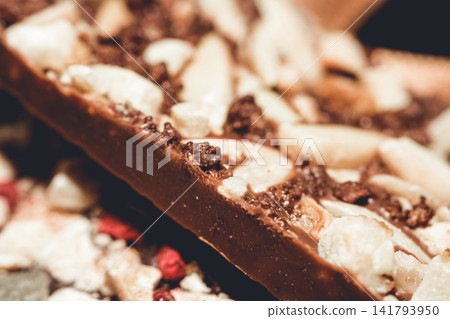 Delicious handmade artisan chocolate bar with nuts and dried fruit close-up luxury treat Delicious handmade artisan chocolate bar with nuts and dried fruit close-up luxury treat 141793950
