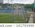 Close up view of metal training soccer goals with nets placed on side of green artificial grass football field with blue seats in background 141793990