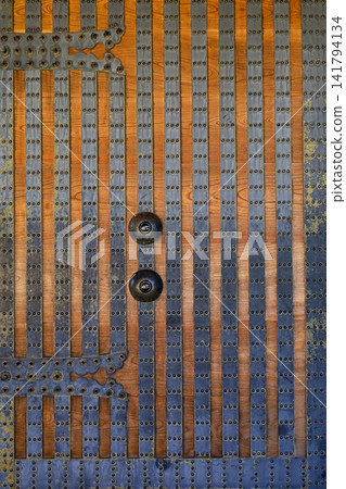 Ancient Wooden Door with Iron Studs Rivets and Ornate Metal Handles Close Up Ancient Wooden Door with Iron Studs Rivets and Ornate Metal Handles Close Up 141794134