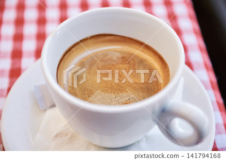 Close-up view of freshly brewed hot coffee in a white cup on a saucer Close-up view of freshly brewed hot coffee in a white cup on a saucer 141794168
