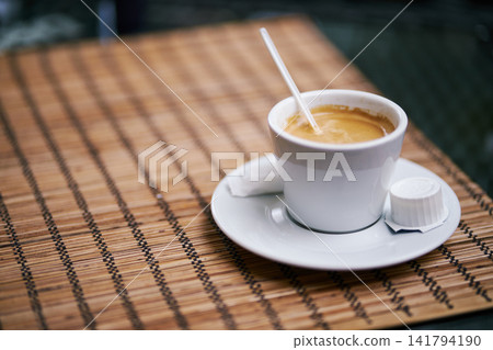 Close-up of a white ceramic cup filled with aromatic espresso on a bamboo placemat Close-up of a white ceramic cup filled with aromatic espresso on a bamboo placemat 141794190