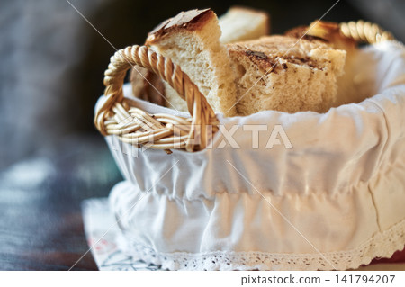 Freshly sliced artisan bread served in a small woven basket with white cloth lining Freshly sliced artisan bread served in a small woven basket with white cloth lining 141794207