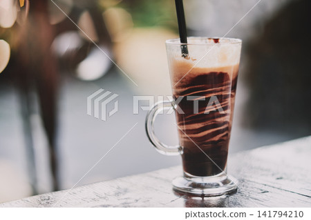 Close-up of a refreshing iced chocolate drink served in a tall glass with a straw Close-up of a refreshing iced chocolate drink served in a tall glass with a straw 141794210