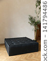 Modern black tufted leather square ottoman in minimalist bright interior with sunlight 141794486