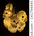 Halloween glowing yellow skull string lights hanging in the dark 141794495