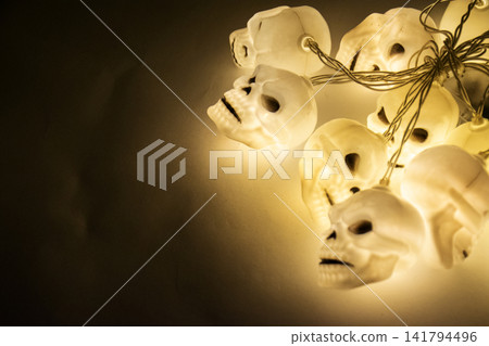 Halloween glowing yellow skull string lights hanging in the dark Halloween glowing yellow skull string lights hanging in the dark 141794496