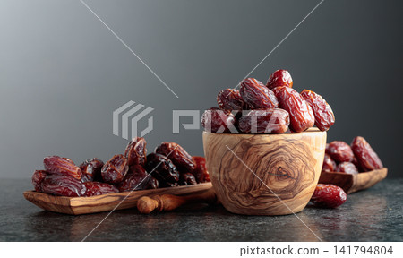 Dates fruit in wooden dish on a black table. 141794804