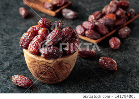 Dried dates fruit on a black stone table. Dried dates fruit on a black stone table. 141794805