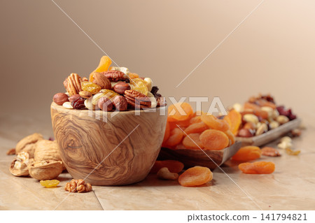 Dried fruits and nuts on a beige ceramic table. Dried fruits and nuts on a beige ceramic table. 141794821