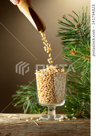 Pine nuts is poured in a glass bowl. Pine nuts is poured in a glass bowl. 141794828