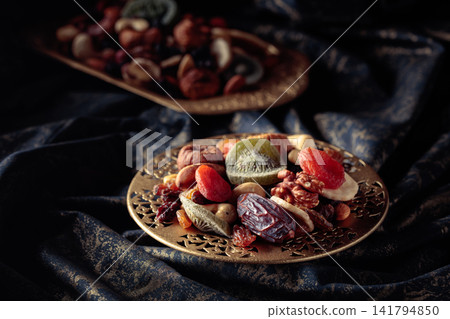 Dried tropical fruits and nuts in a golden bowl. Dried tropical fruits and nuts in a golden bowl. 141794850