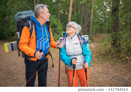 Hiking tourism adventure. Senior couple man woman enjoying outdoor recreation hiking in forest. Happy old people backpackers hikers enjoy walking hike trekking tourism active vacation beauty of nature Hiking tourism adventure. Senior couple man woman enjoying outdoor recreation hiking in forest. Happy old people backpackers hikers enjoy walking hike trekking tourism active vacation beauty of nature 141794914