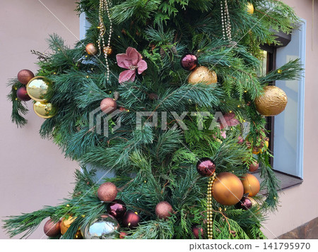 Spruce branches on the facade of the house, decorated with Christmas ornaments. The concept of Christmas and the New Year. Spruce branches on the facade of the house, decorated with Christmas ornaments. The concept of Christmas and the New Year. 141795970