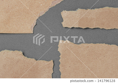 Torn Recycled Cardboard Pieces on Gray Background. Pieces of torn brown cardboard arranged on dark gray surface, copy space. Recycled paper texture, collage, packaging, sustainability craft design Torn Recycled Cardboard Pieces on Gray Background. Pieces of torn brown cardboard arranged on dark gray surface, copy space. Recycled paper texture, collage, packaging, sustainability craft design 141796128