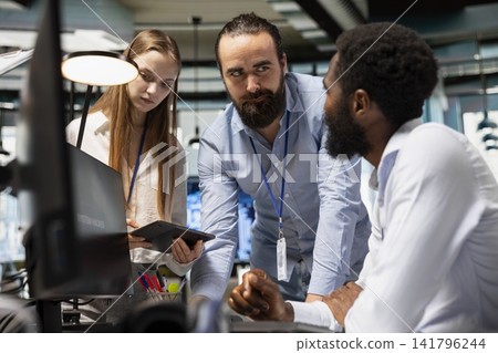 Team of technicians helping employee stop hacker intrusion in office. Tech startup staff members colleagues reacting to system breach notification, coordinating incident response for network attack Team of technicians helping employee stop hacker intrusion in office. Tech startup staff members colleagues reacting to system breach notification, coordinating incident response for network attack 141796244